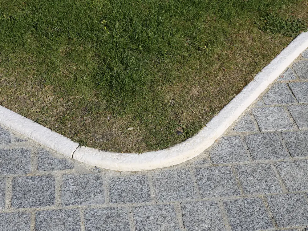 Bordure courbe en pierre entre gazon et pavés
