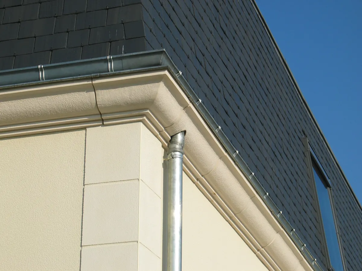 Corniche doucine en angle sous une toiture en ardoise