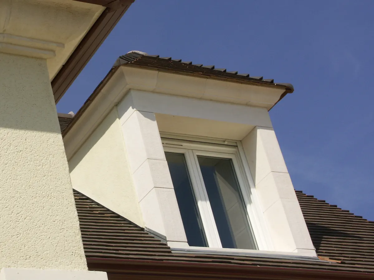Lucarne en pierre reconstituée sur un toit de tuiles