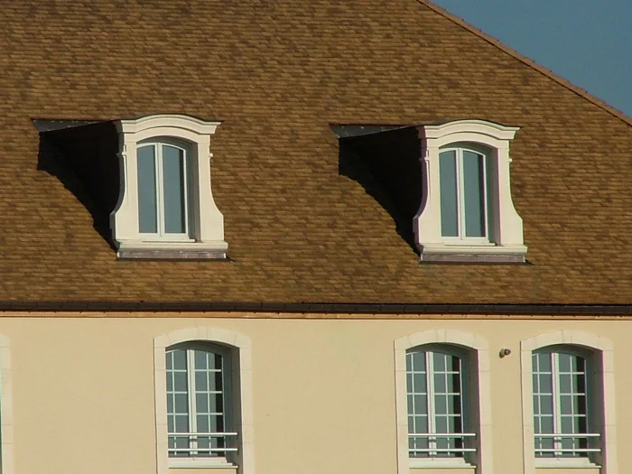 Deux lucarnes à chapeau de gendarme LDC84 sur un toit de tuiles, au-dessus d'une façade enduite