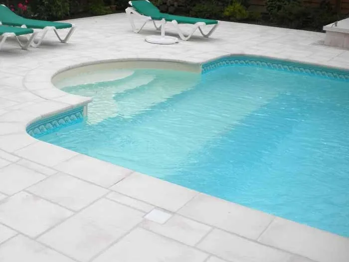 Margelles patinées autour d'une piscine avec escalier