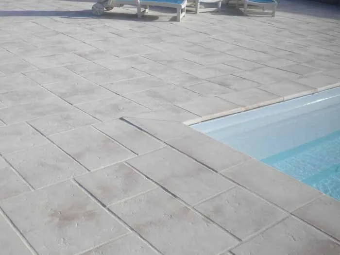Margelles et dallage patinés au bord d'une piscine