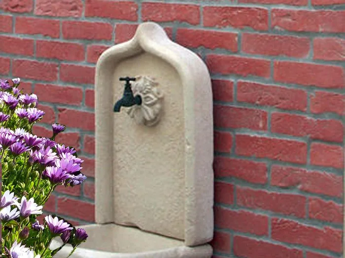 Mur habillé de parement brique rouge derrière une fontaine murale