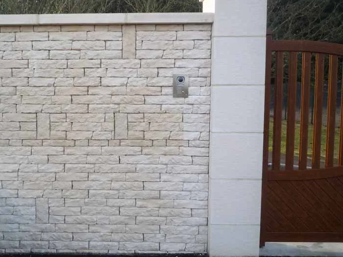 Pilier bouchardé coiffé d'une pointe diamant, le long d'un mur en pierre